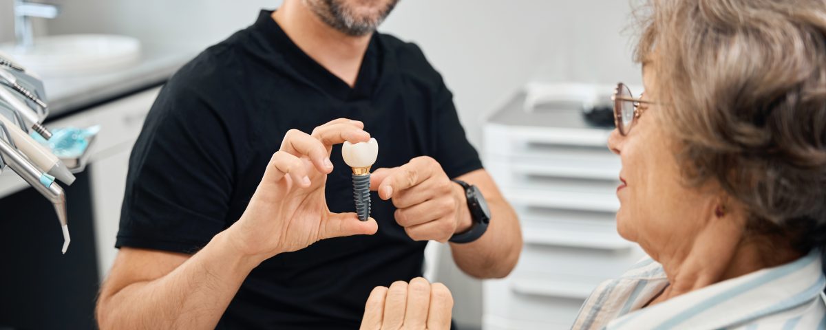 Dentist showing patient a dental implant model.