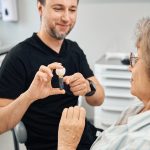 Dentist showing patient a dental implant model.